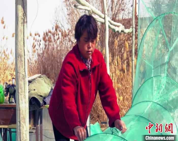 渔民李英查看刚刚织好的新网。 都古尔加甫 摄 “促民增收打更多的鱼”中国最大内陆淡水湖博斯腾湖进入禁渔期